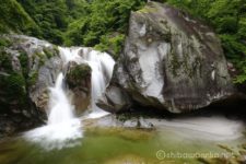 水線を高巻いたり近づいたりしながら渓谷道をゆくと、渓谷道沿いに明確な滝の存在を感じます。
渓谷道から下りてゆくと、大岩から二筋に流れ落ちる豪快な滝が三の滝です。
三の滝の前方の大岩から真正面に眺めることができます。