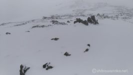 12:00 準備を整えて間ノ岳山頂発。
間ノ岳の山頂はだだっ広い。
あたり一面雲に覆われて視界が効かず、今日1回目のホワイトアウト状態。
先行者のトレースも既に風に消されて、どちらに行って良いかも分からない。
気が動転したのか、手前の尾根から下り始める。
しかし嫌な予感がする。